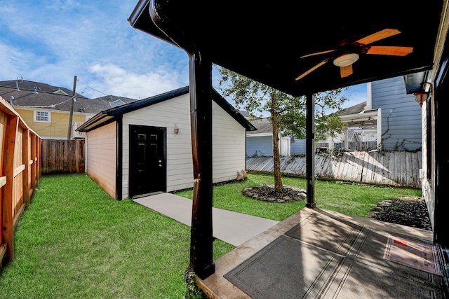 view of yard with a fenced backyard, an outdoor structure, a ceiling fan, and a patio area