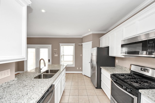 kitchen featuring ornamental molding, a sink, appliances with stainless steel finishes, white cabinets, and light tile patterned floors