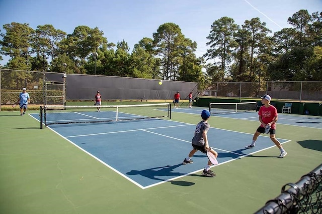 view of tennis court with community basketball court and fence