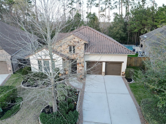 view of front facade with a tile roof, stucco siding, driveway, and an attached garage