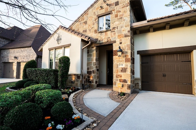 view of front facade featuring stucco siding, concrete driveway, a garage, stone siding, and a tile roof