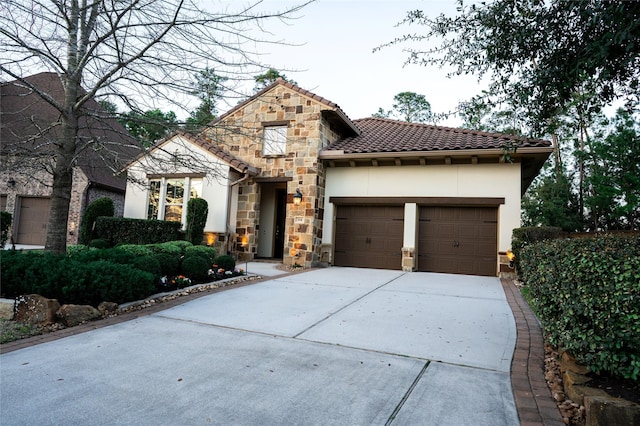 view of front facade with stucco siding, a tile roof, stone siding, concrete driveway, and a garage