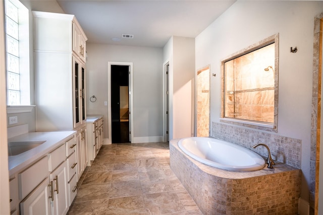 bathroom featuring vanity, a bath, baseboards, and visible vents