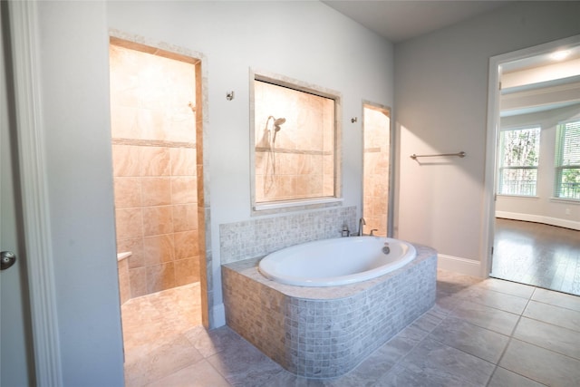 bathroom featuring baseboards, walk in shower, a bath, and tile patterned flooring