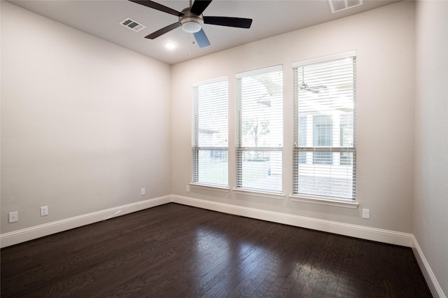 spare room with visible vents, baseboards, dark wood-style floors, and ceiling fan