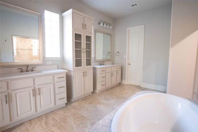 bathroom with a sink, visible vents, two vanities, and a tub