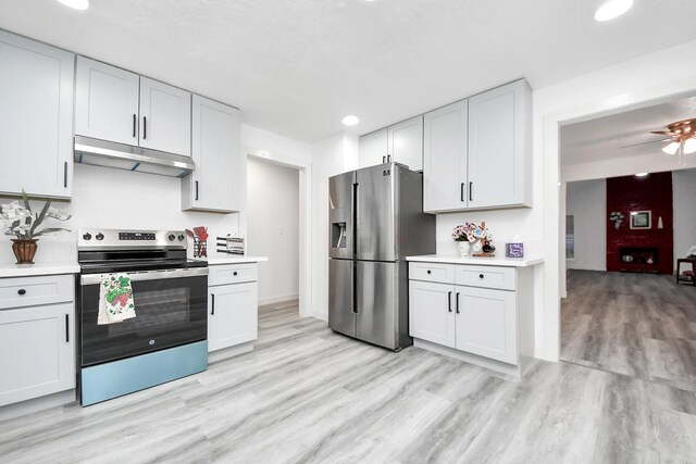 kitchen with under cabinet range hood, light wood-type flooring, stainless steel appliances, and light countertops