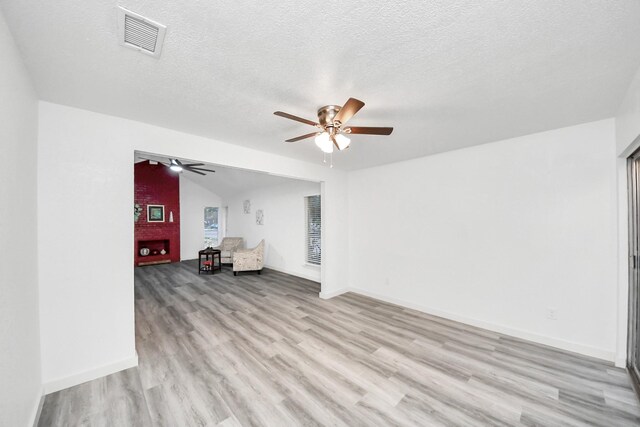 unfurnished living room featuring a ceiling fan, baseboards, visible vents, light wood-style flooring, and a textured ceiling