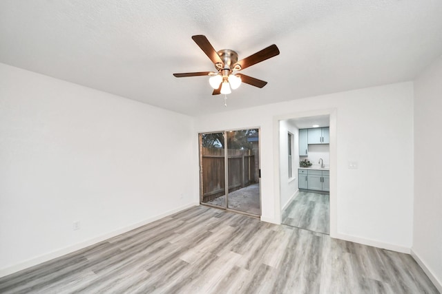 unfurnished bedroom with light wood-style flooring, access to outside, a sink, baseboards, and ceiling fan