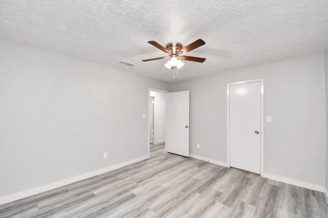 unfurnished bedroom featuring visible vents, a textured ceiling, light wood finished floors, baseboards, and ceiling fan