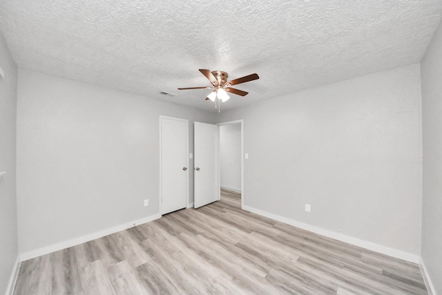 unfurnished bedroom featuring visible vents, ceiling fan, baseboards, light wood-type flooring, and a textured ceiling