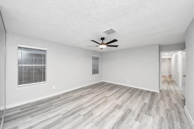 unfurnished room with a ceiling fan, baseboards, visible vents, light wood-style floors, and a textured ceiling