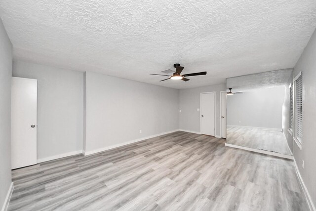 unfurnished living room featuring baseboards, a textured ceiling, wood finished floors, and a ceiling fan