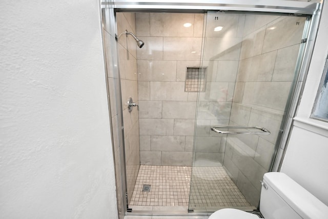 full bath featuring a shower stall, toilet, and a textured wall