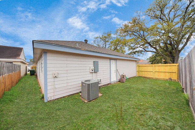 back of house featuring a yard, central AC, and a fenced backyard