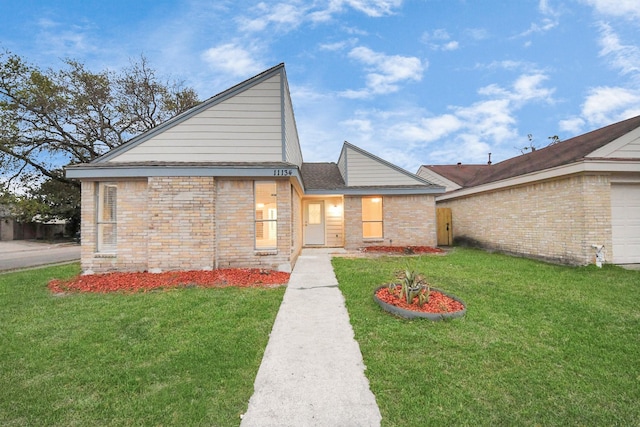 view of front of house with brick siding, a shingled roof, and a front yard