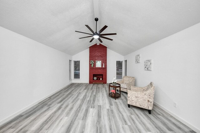 unfurnished room with wood finished floors, a ceiling fan, a fireplace, vaulted ceiling, and a textured ceiling