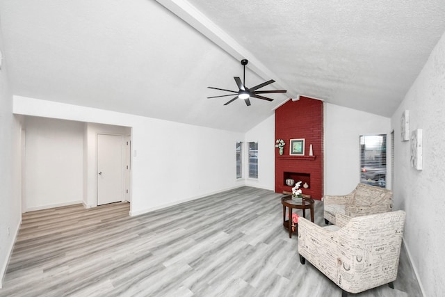 sitting room with a ceiling fan, lofted ceiling with beams, a textured ceiling, wood finished floors, and a fireplace