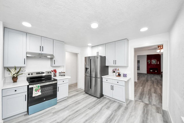 kitchen with under cabinet range hood, light wood-type flooring, light countertops, appliances with stainless steel finishes, and a textured ceiling