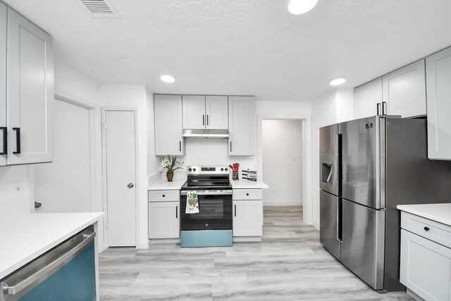 kitchen with visible vents, light wood-type flooring, under cabinet range hood, appliances with stainless steel finishes, and light countertops