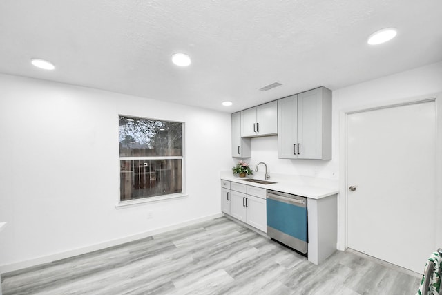 kitchen with visible vents, light countertops, dishwashing machine, light wood-style flooring, and a sink