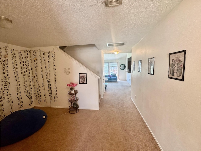 hall with light carpet, visible vents, stairs, and baseboards