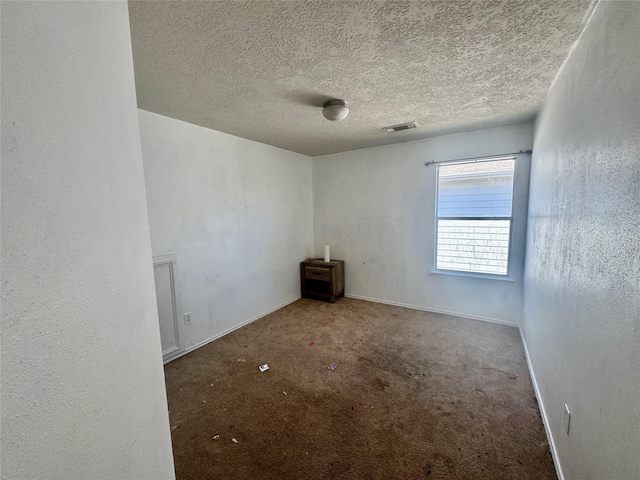 spare room featuring visible vents, baseboards, a textured ceiling, and carpet flooring