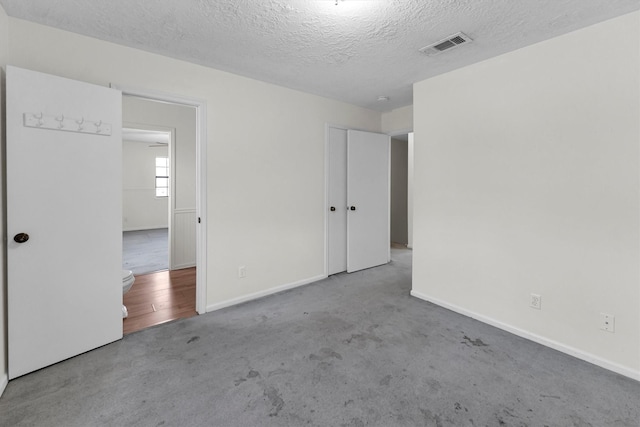 unfurnished bedroom with visible vents, baseboards, a textured ceiling, and carpet