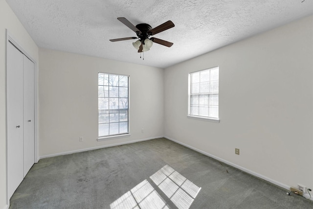 unfurnished bedroom with a textured ceiling, a closet, carpet flooring, baseboards, and ceiling fan