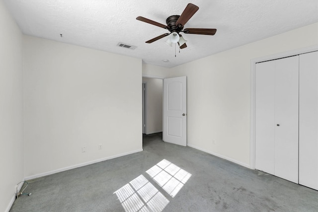 unfurnished bedroom with visible vents, carpet floors, a textured ceiling, and a closet