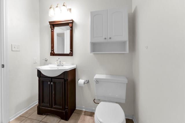 half bath with baseboards, toilet, and vanity