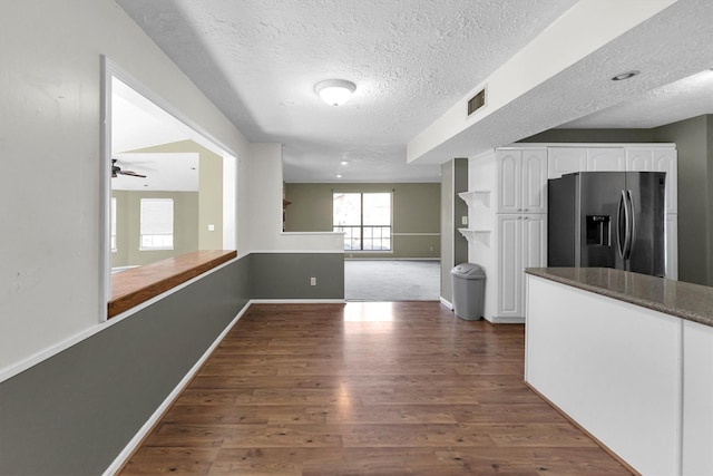 kitchen with visible vents, white cabinetry, dark wood finished floors, stainless steel refrigerator with ice dispenser, and a textured ceiling