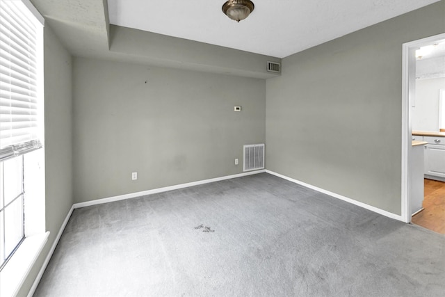 unfurnished room featuring carpet flooring, baseboards, visible vents, and a healthy amount of sunlight