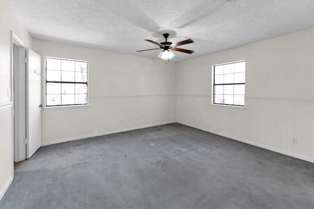 unfurnished room with a ceiling fan, a healthy amount of sunlight, and wainscoting