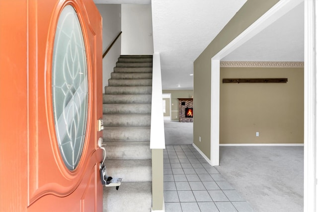 foyer with light carpet, a textured ceiling, stairway, light tile patterned floors, and baseboards