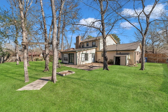 back of house with a patio, a lawn, a chimney, and fence