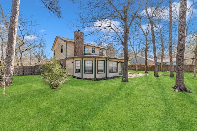 back of property featuring a yard, a fenced backyard, and a chimney