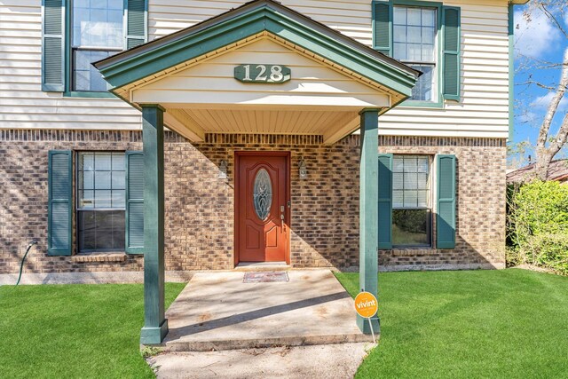 entrance to property with a lawn and brick siding