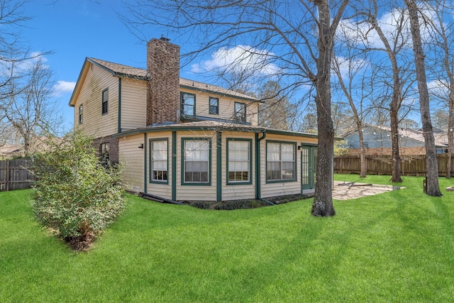 back of house featuring a lawn, a chimney, and fence