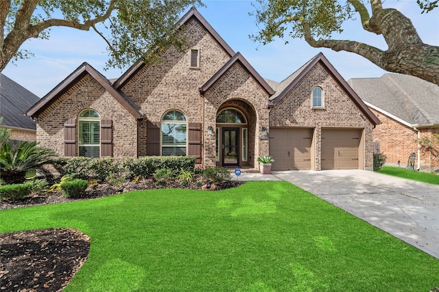 french country inspired facade featuring a front lawn, a garage, brick siding, and driveway