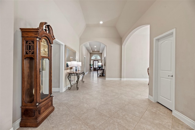 corridor with arched walkways, recessed lighting, baseboards, and lofted ceiling