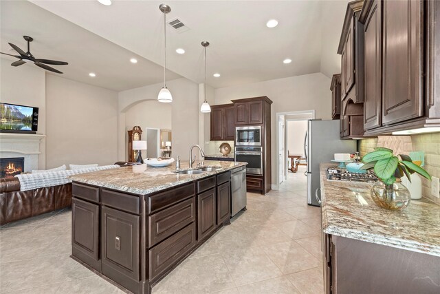 kitchen featuring visible vents, dark brown cabinetry, open floor plan, appliances with stainless steel finishes, and a sink