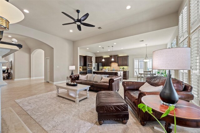 living room featuring baseboards, recessed lighting, arched walkways, and ceiling fan