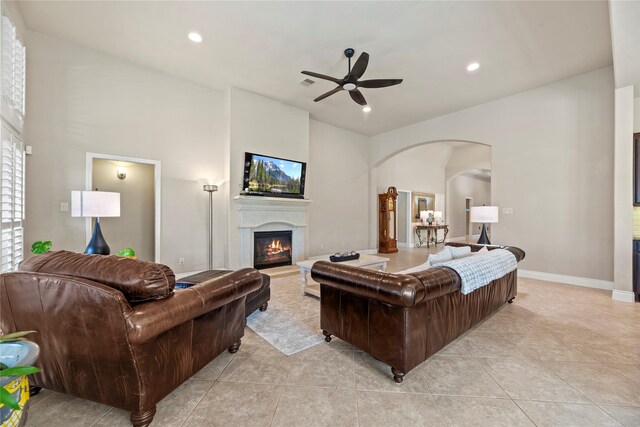 living area with a glass covered fireplace, recessed lighting, a ceiling fan, and arched walkways