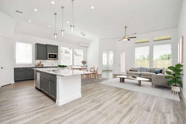 kitchen featuring gray cabinetry, ceiling fan, built in microwave, dishwasher, and a sink