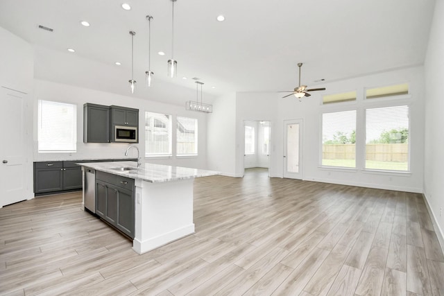 kitchen featuring built in microwave, dishwasher, gray cabinets, a ceiling fan, and a sink