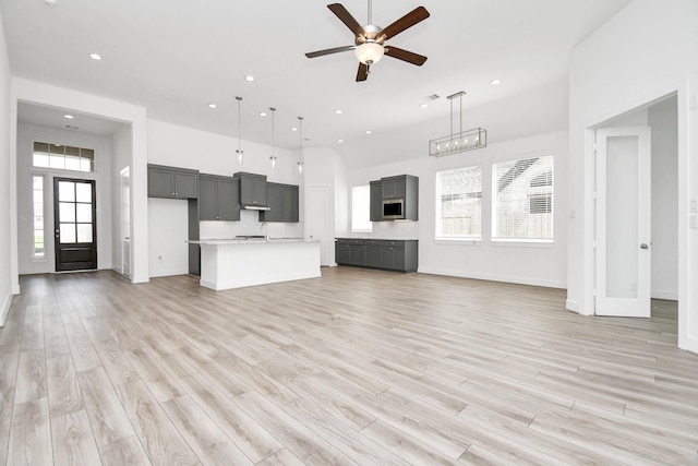 unfurnished living room with recessed lighting, light wood-style flooring, a high ceiling, and ceiling fan