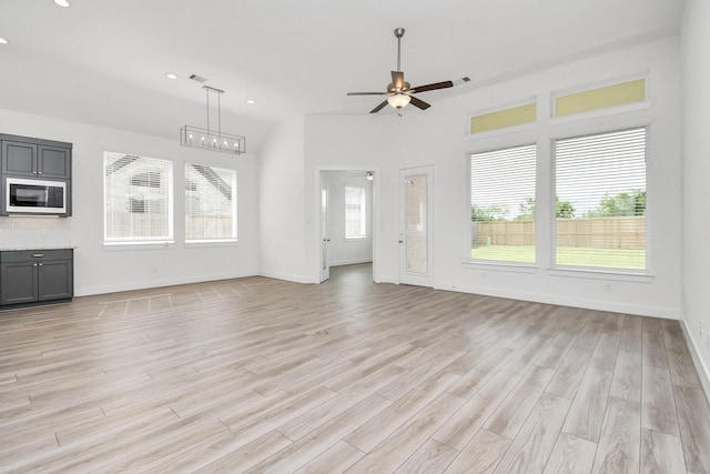 unfurnished living room with plenty of natural light, a ceiling fan, and light wood-style floors