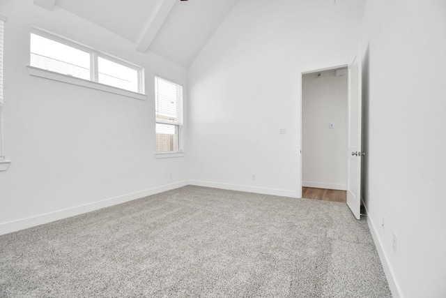 carpeted empty room featuring beam ceiling, baseboards, and high vaulted ceiling