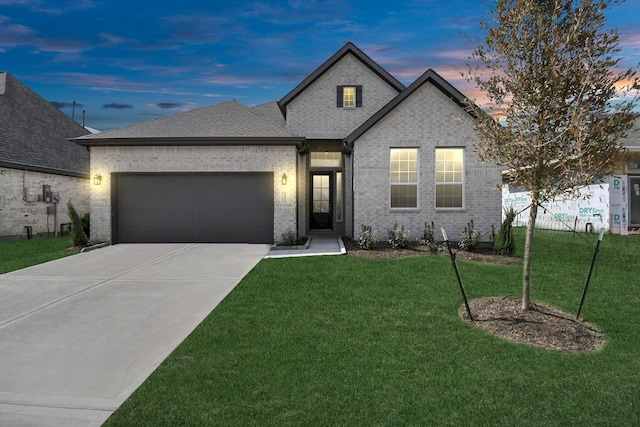 view of front of property featuring a front lawn, an attached garage, brick siding, and driveway